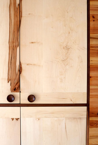 Bright wooden cabinet with dark wooden knobs and grain pattern. Close shot front.