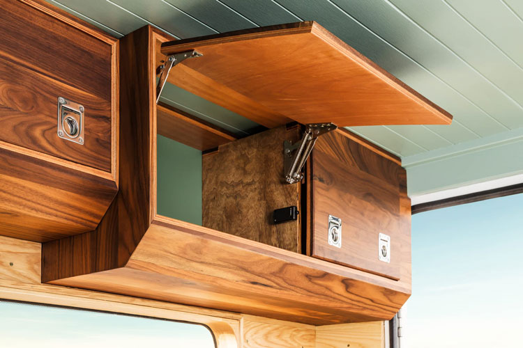 Campervan integrated cabinet system with wooden workdesk, shelving and cabinet system.