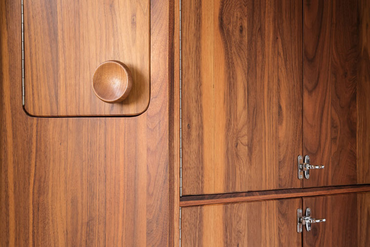 Bright wooden cabinet with dark wooden knobs and grain pattern. Close shot front.