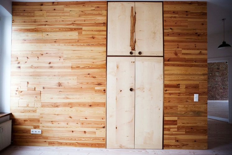 Front view on interior wood wall, with large integrated cabinet in right center. Design combination of dark and light wood.