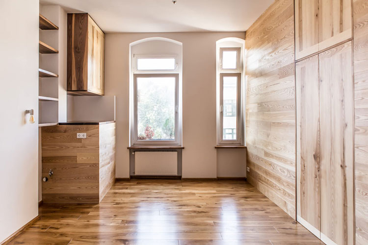 Living room with wooden floor and wooden side wall with integrated cabinet. Front view.