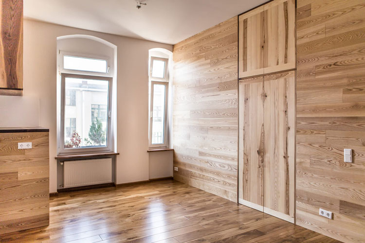 Living room with wooden floor and wooden side wall with integrated cabinet. Angular view.
